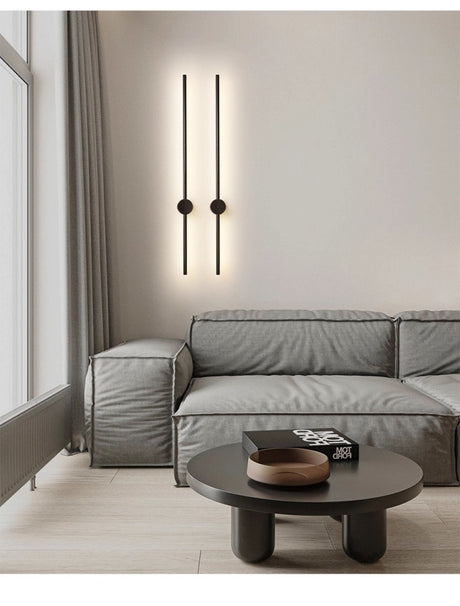 A black pair lit above a sofa and a round coffee table with a tray on it