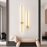A gold pair lit above a curved bench beside a tall mirror and a dark wall