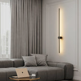 Lit beside a gray sofa with a laptop on a side table and a long curtain behind