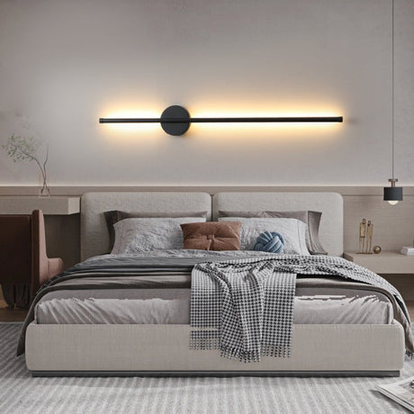Lit horizontally above a bed with a padded headboard and folded throw