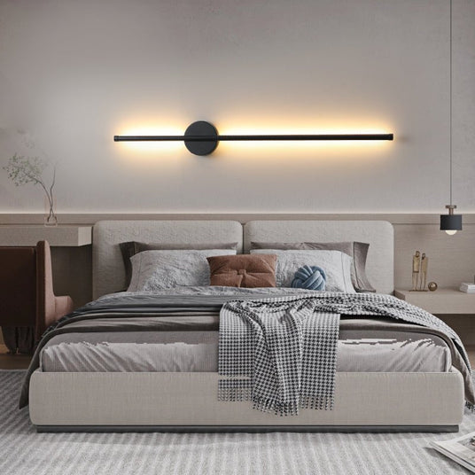 Lit horizontally above a bed with a padded headboard and folded throw