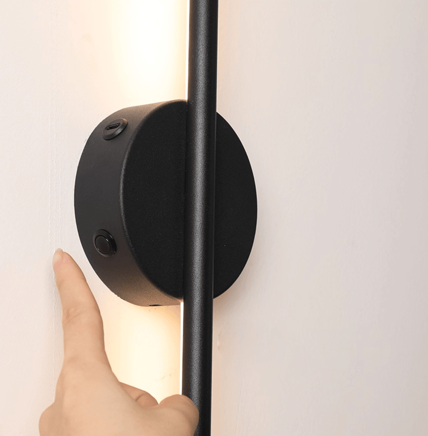 A hand touching the round hub to switch the bar on against a white wall