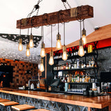 Lit along a bar counter with bottles on shelving and stools in front
