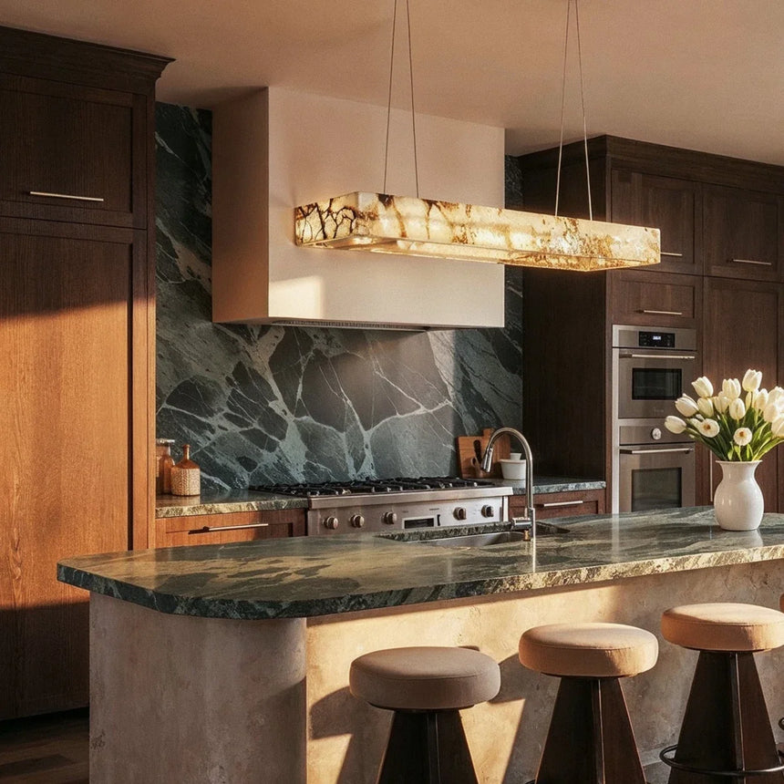 A lit bar above a kitchen island with a green stone backsplash