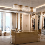 The lit bar above a gold kitchen counter in a room with floor to ceiling windows