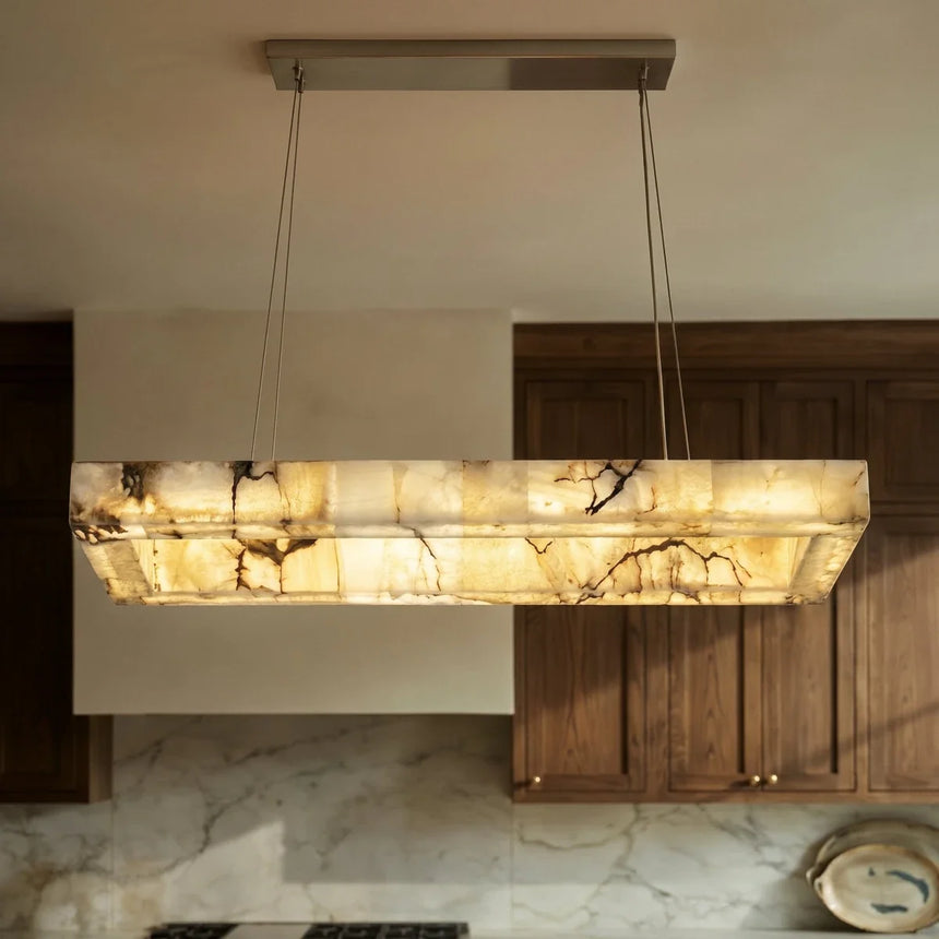 A lit stone bar above a marble counter in a fitted kitchen