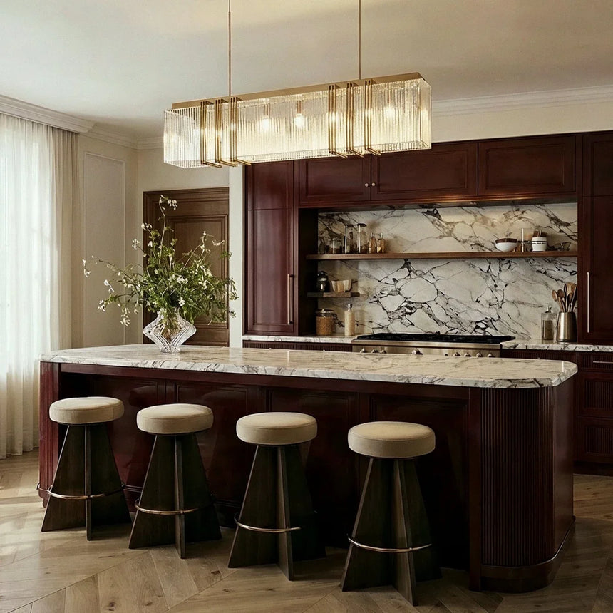 The long version lit above a marble kitchen island with four upholstered stools