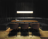 The flat lit bar hung above a dining table in a dark panel lined room