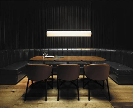 The flat lit bar hung above a dining table in a dark panel lined room