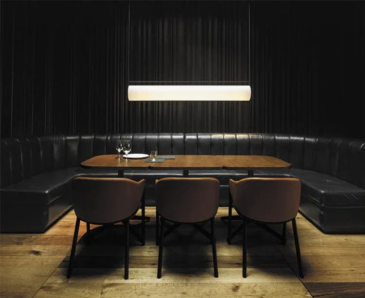 The flat lit bar hung above a dining table in a dark panel lined room