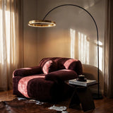 The gold ring lit beside a velvet armchair by curtains, a side table below