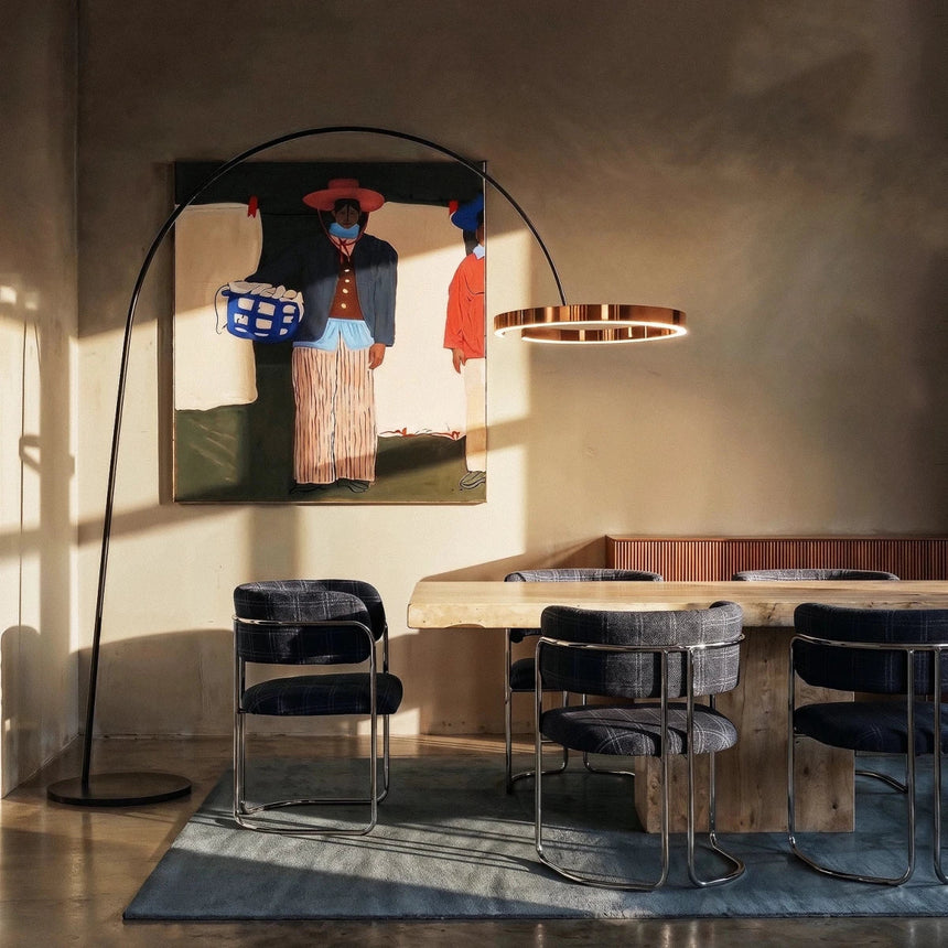 Two of the lamps lit over a dining table with chairs, a rug and a framed picture