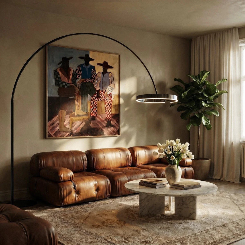 The gold ring lit over a leather sofa in a living room with artwork and a plant