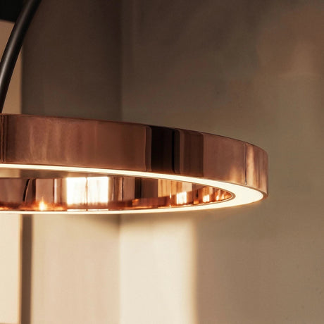 The rose gold ring from the side, the lit inner edge reflected in the metal