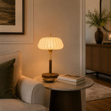 Remote control table lamp lit on a round table beside a pale sofa