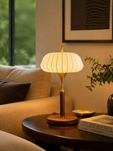 Remote control table lamp lit on a round table in a pale living room