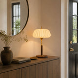 Remote control table lamp lit on a sideboard below a round mirror