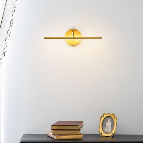 Gold arm lit above a black chest of drawers with books and a small gilt frame