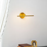 Gold arm lit above a small framed picture and a stack of books on a dark chest