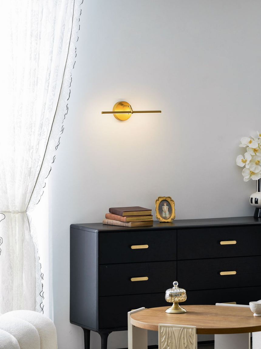 Gold arm lit on a wall above a black sideboard beside a curtain and a round table