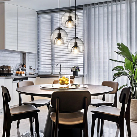 Three domes lit above a round kitchen table with chairs and a window