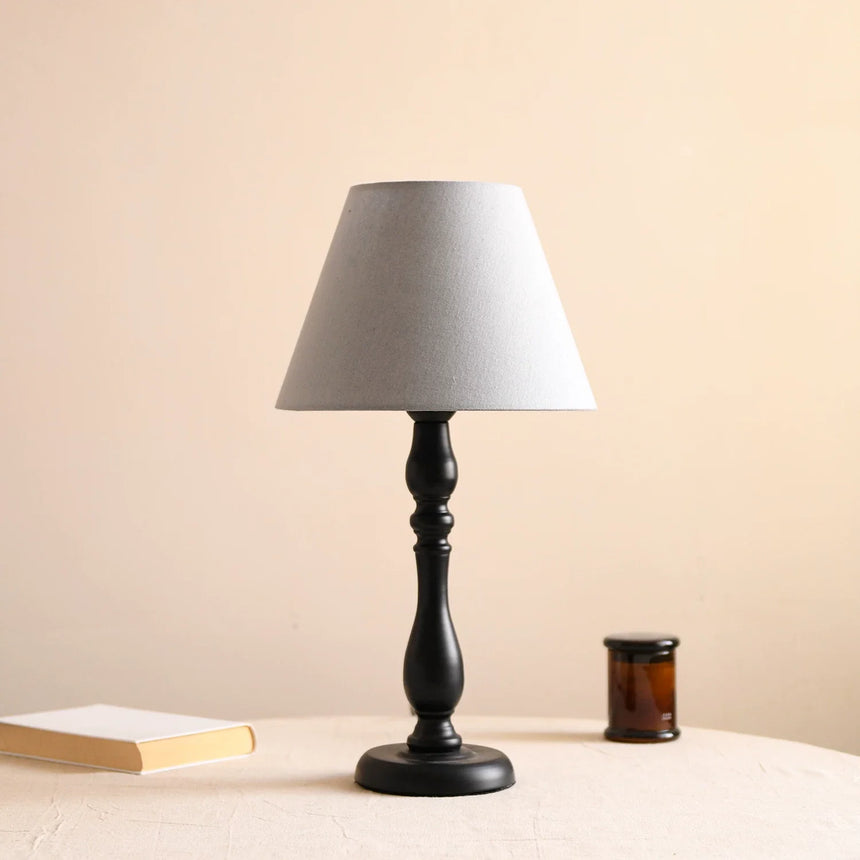 Table lamp with a muted blue shade on a turned black base, unlit