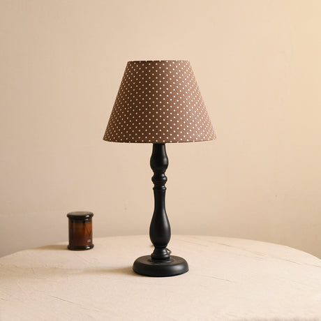 Table lamp with a brown polka dot shade on a turned black base