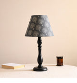 Table lamp with a dark shade printed with pale birch trees, lit