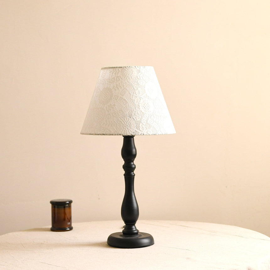 Table lamp with an off white shade finished with a lace edge trim