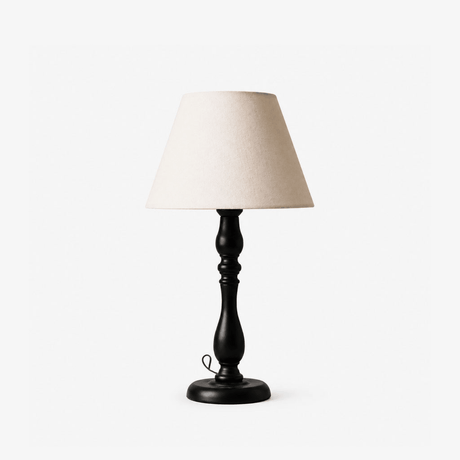 Table lamp with a turned black base and a plain cream tapered shade