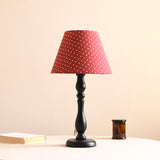 Table lamp with a red shade printed with small polka dots, unlit