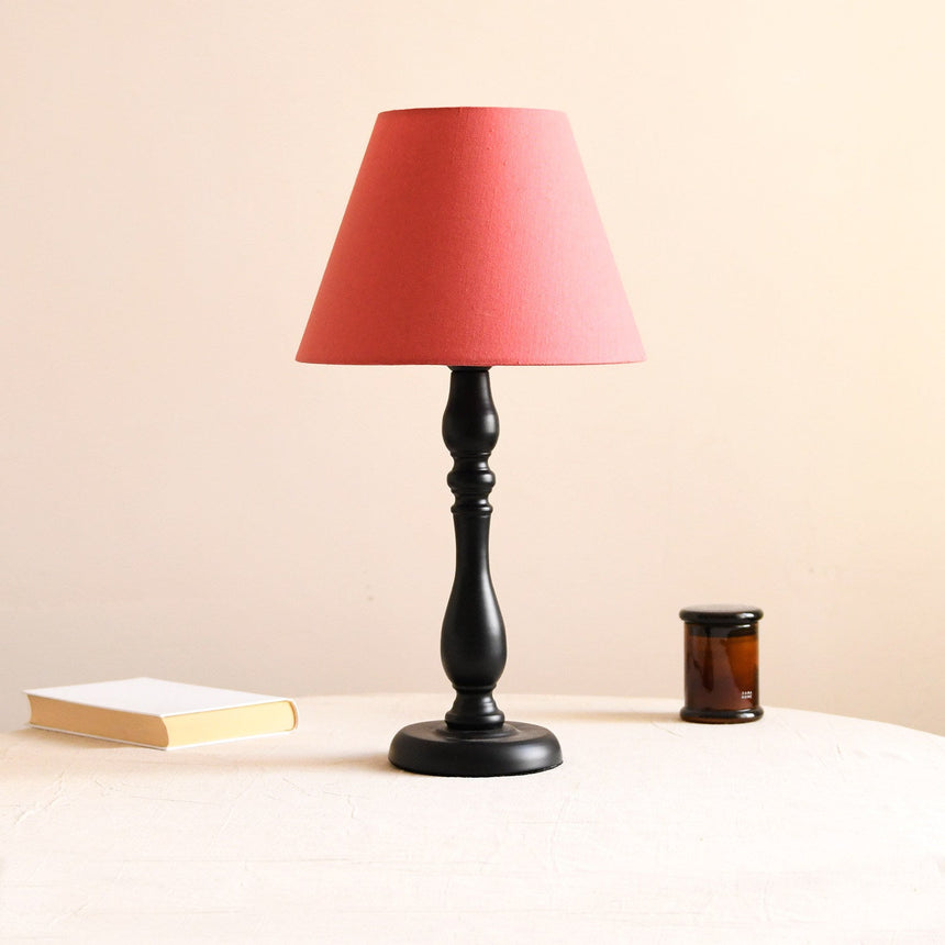 Table lamp with a solid washed red shade on a turned black base