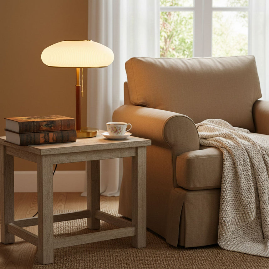 Ribbed glass table lamp lit on a side table beside an armchair