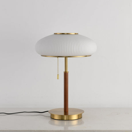 Full view of the ribbed glass table lamp against a pale ground
