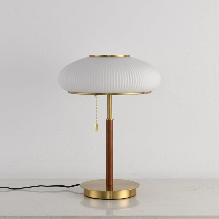 Full view of the ribbed glass table lamp against a pale ground