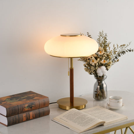Ribbed glass table lamp lit and seen at an angle beside flowers