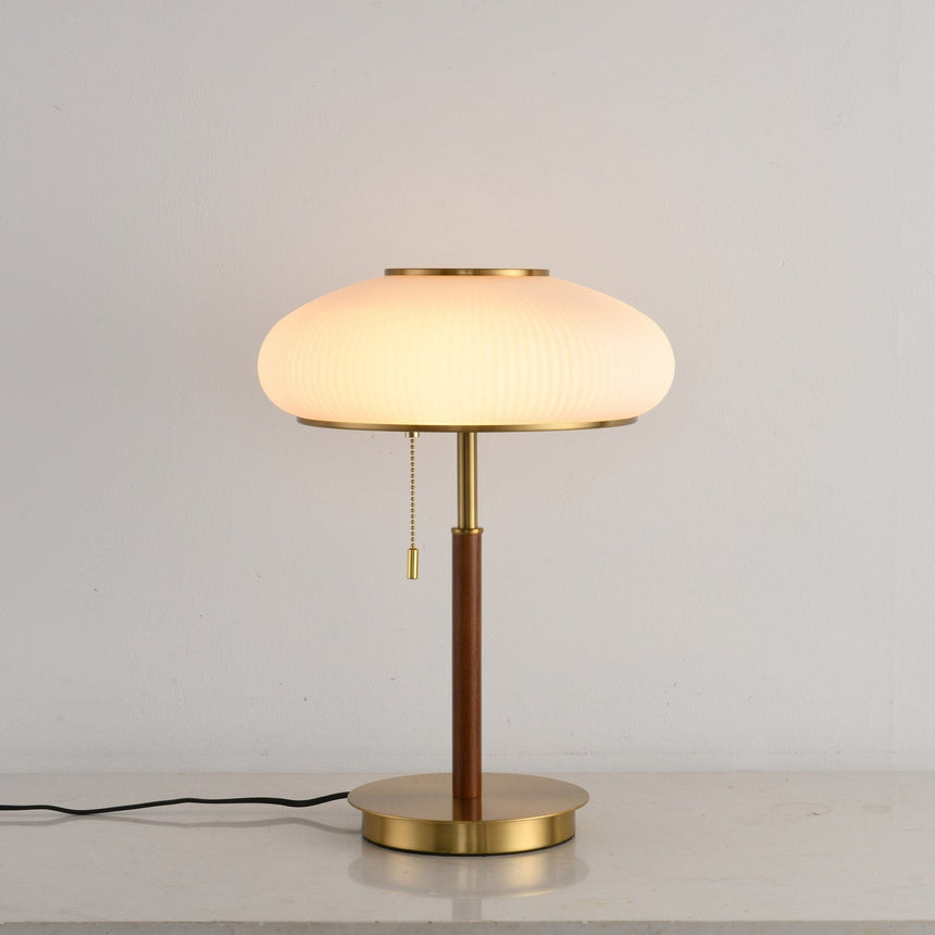 Ribbed glass table lamp lit from the front, the pull chain in view