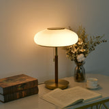 Ribbed glass table lamp lit warm beside dried flowers