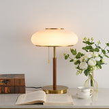 Ribbed glass table lamp lit beside an open book and a cup