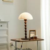 Rice paper table lamp lit on a table in a pale room with a dresser
