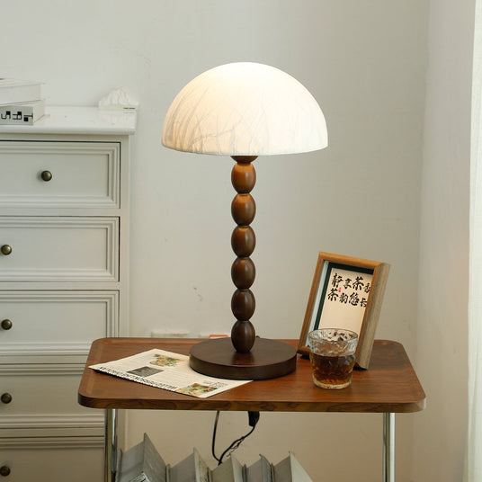 Rice paper table lamp lit on a wooden table beside a framed card