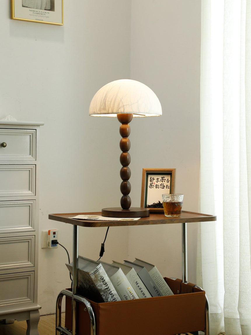 Rice paper table lamp lit on a table seen across a pale room