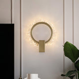 The ring lit on a pale wall above a white vase and a large leaf plant