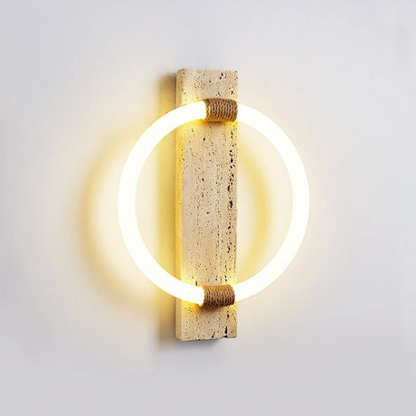 The sconce seen at an angle, the ring standing off the stone and lighting the wall