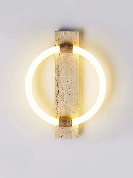 The ring sconce lit on a gray wall, the light spreading in a soft halo
