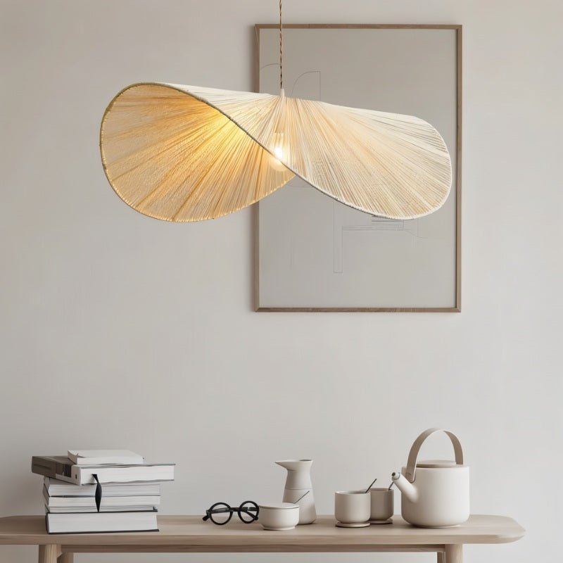 The shade lit above a console with stacked books, a teapot and pale ceramics