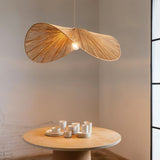 The pale shade lit above a round wood table set with pale cups and a jug
