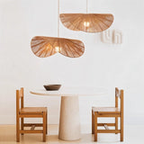 The shade lit above a leather sofa beside a framed botanical print and a plant