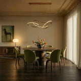 The loops lit above a round dining table with green chairs and cut flowers