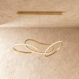 Interlaced illuminated loops in a warm gold finish hung from a slim ceiling bar